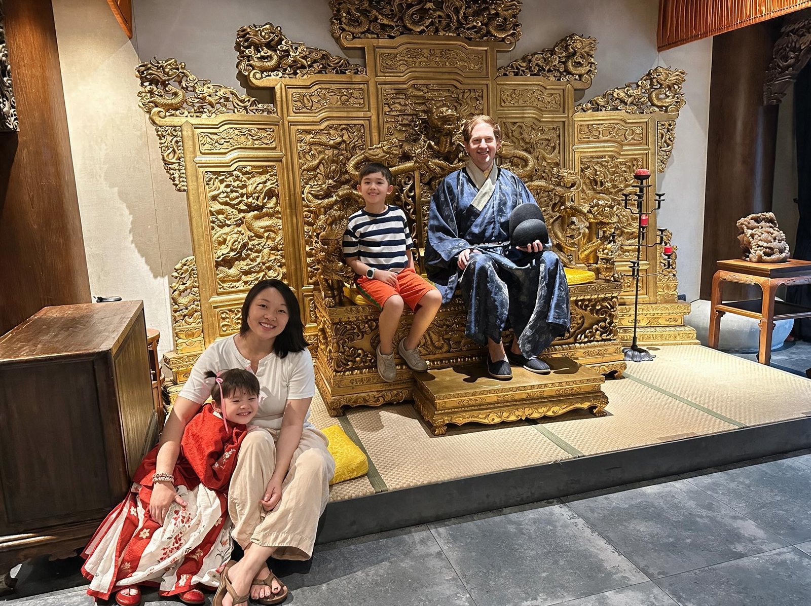 Jane Powell and Brendon, who run One Sixteen East, with their two children in a Chinese antique gallery, the children wearing hanfu beside a gilded dragon throne