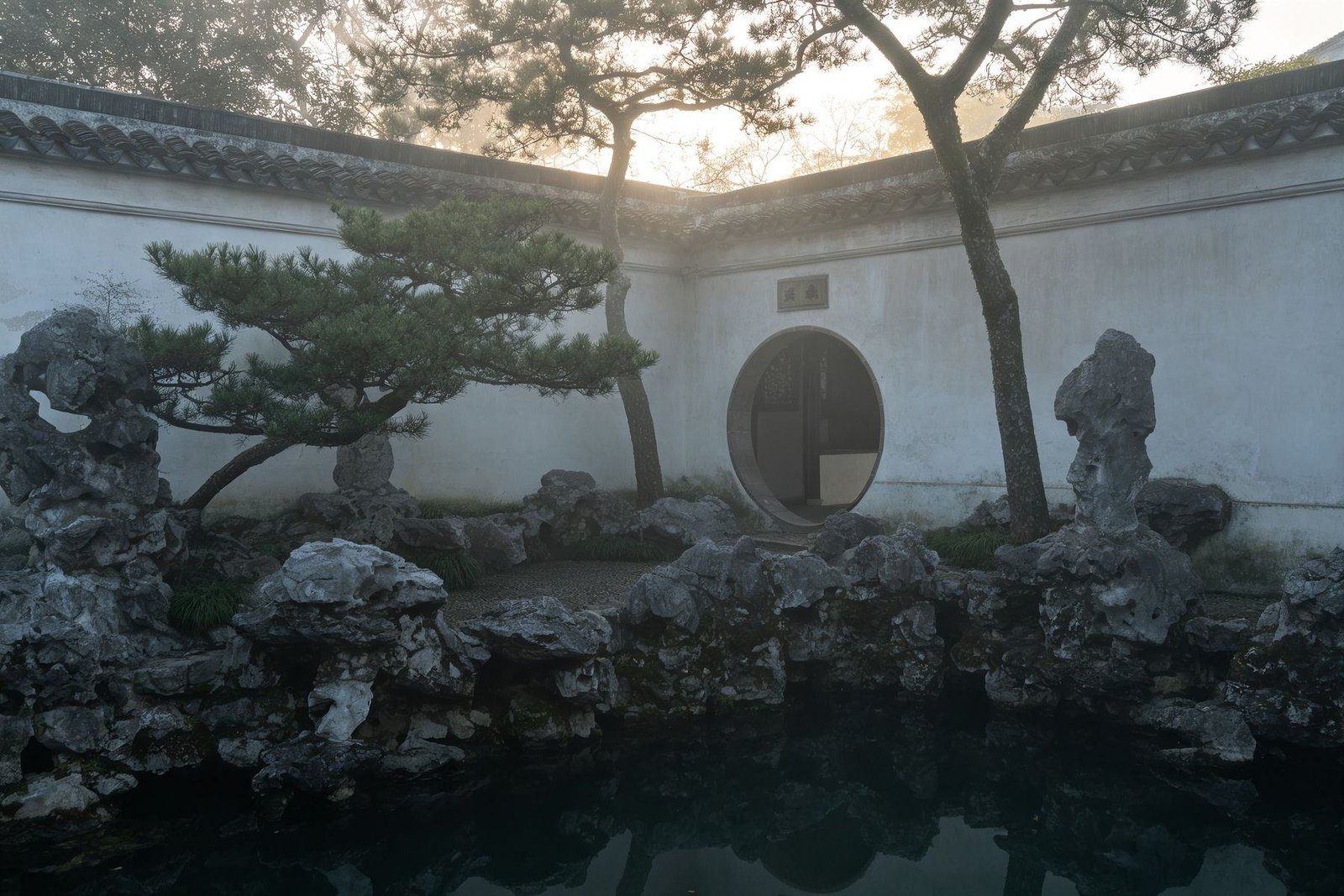 A classical Chinese garden in Suzhou at dawn, empty before opening hours
